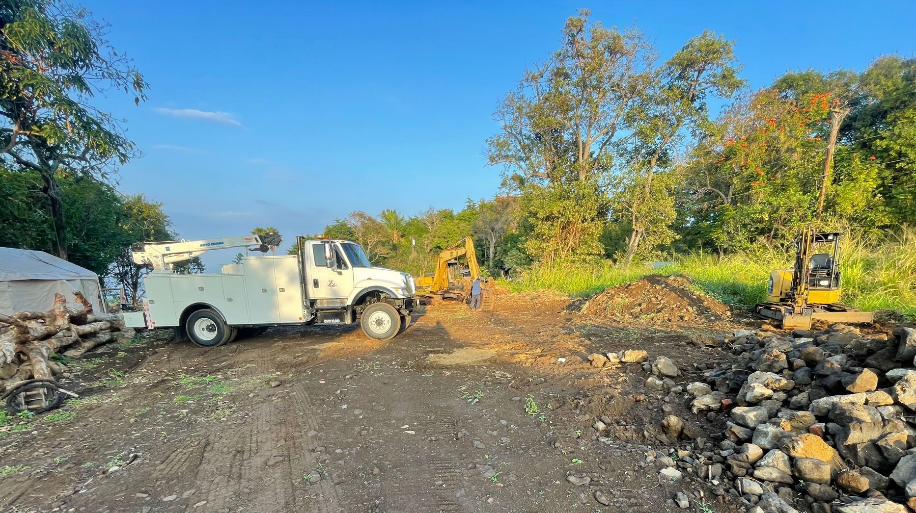 A white truck is parked in a dirt lot next to a pile of rocks.