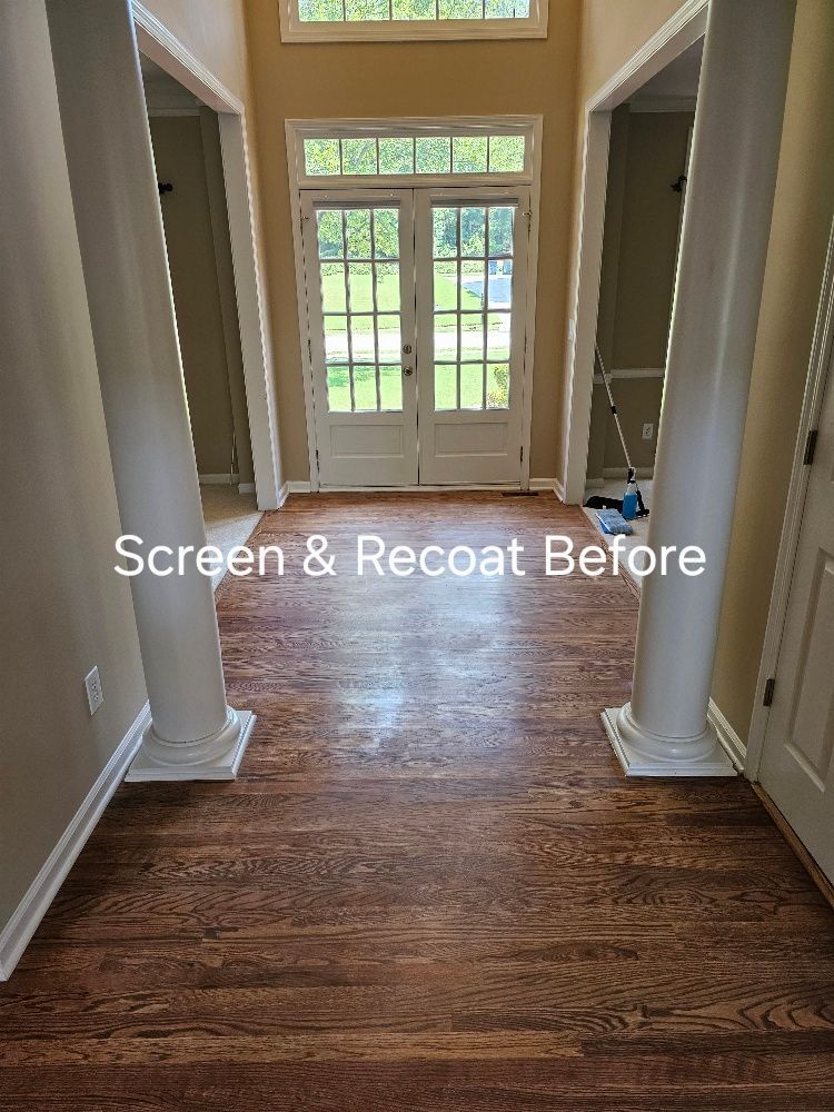 A hallway with hardwood floors and columns in a house.