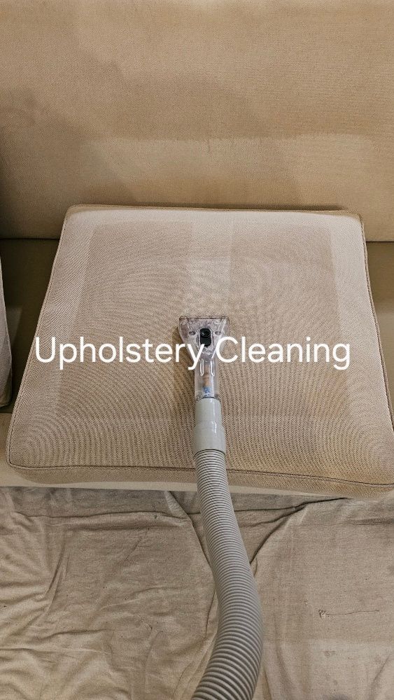 A vacuum cleaner is cleaning a couch in a living room.