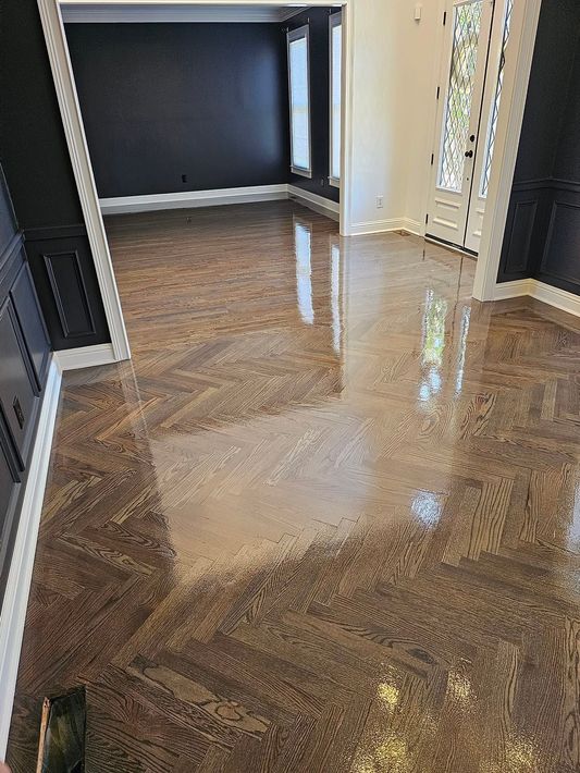 An empty basement with hardwood floors and stairs.