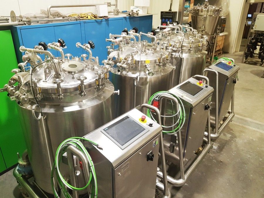 A row of stainless steel tanks sitting next to each other in a room.