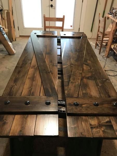 Rustic wooden tabletop with black metal hinges and bolts in a workshop or dining room
