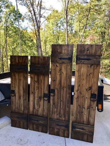 Rustic wooden fence panels leaning on a trailer in a wooded outdoor area