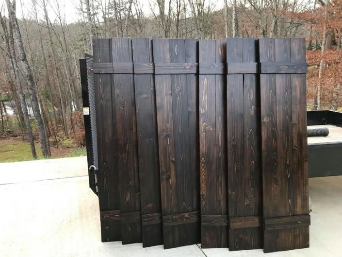 Dark wooden outdoor deck gate or fence panel in a yard, with trees in the background