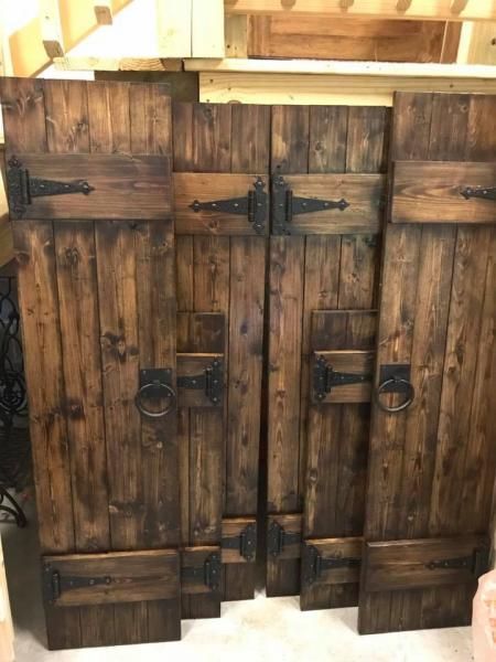 Rustic wooden barn doors with black iron hinges and latches inside a barn-like interior