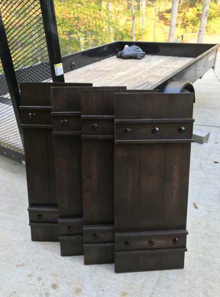 Dark wooden barn-style cabinet or storage chest on a patio, with black hardware and a tray on top