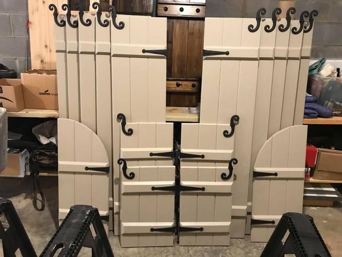 White barn-style double doors with black hardware, shown indoors in a workshop or storage space.