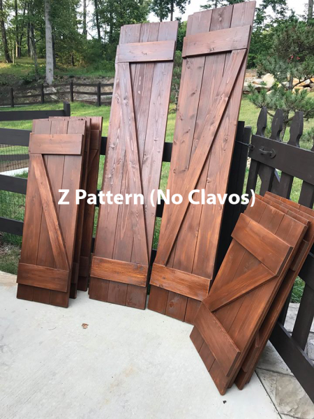 Wooden Z-pattern shutters and panels leaning on a deck, with text “Z Pattern (No Clavos)”.