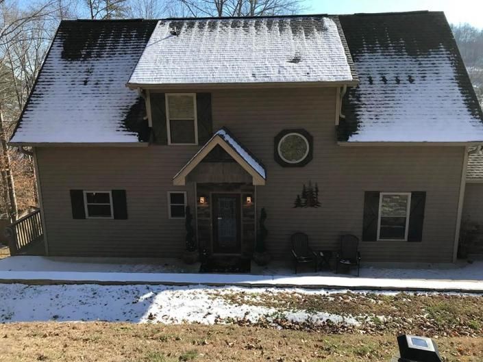 Snow-dusted two-story house with a centered front entrance and circular window above it.