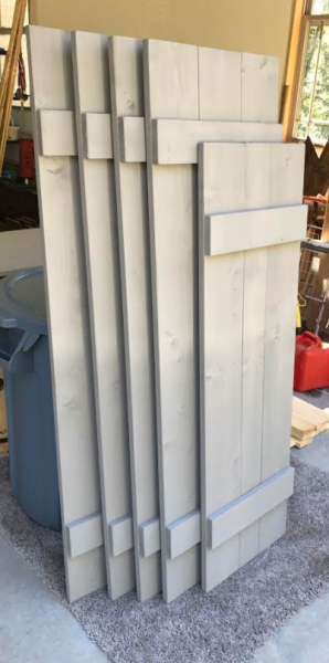Stacked silver metal pipes leaning against a carpeted wall indoors