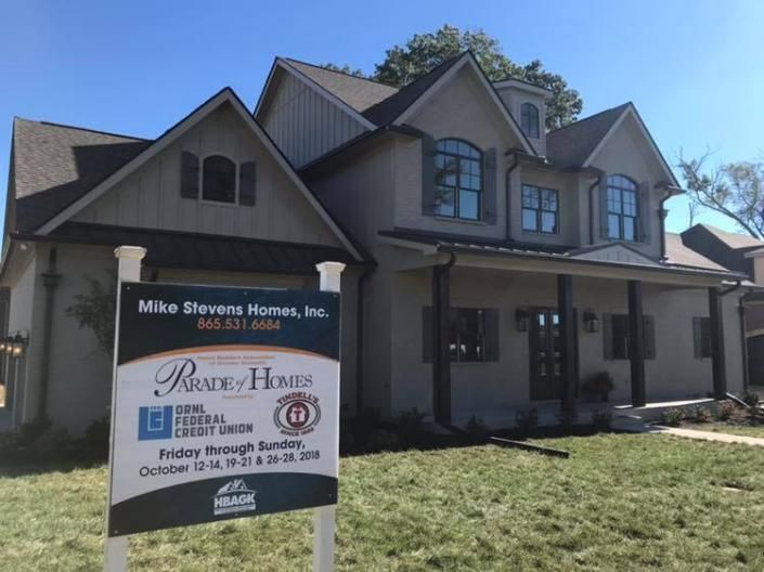 Two-story house with a real estate sign in front on a sunny day