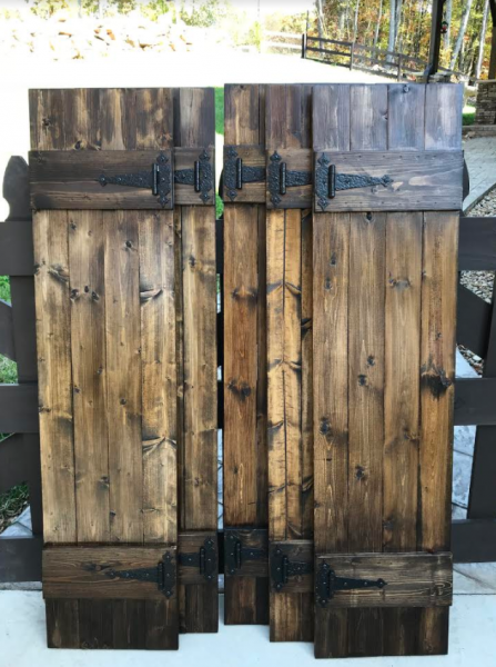 Weathered wooden gate or fence with dark metal hinges and latches outdoors