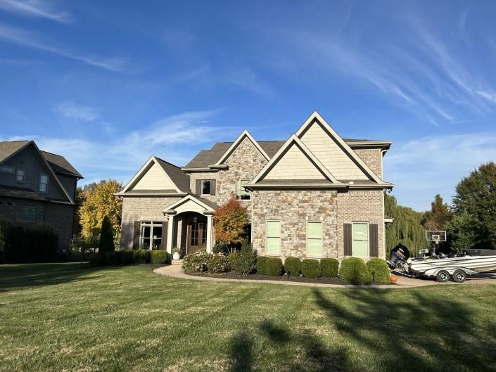 Suburban stone house with manicured lawn and blue sky