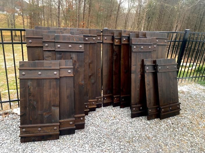 Rustic wooden coffin-style planter boxes displayed outdoors on gravel near a black fence
