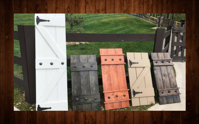 Row of colorful wooden fence gates and shutters on grass, arranged diagonally outdoors.