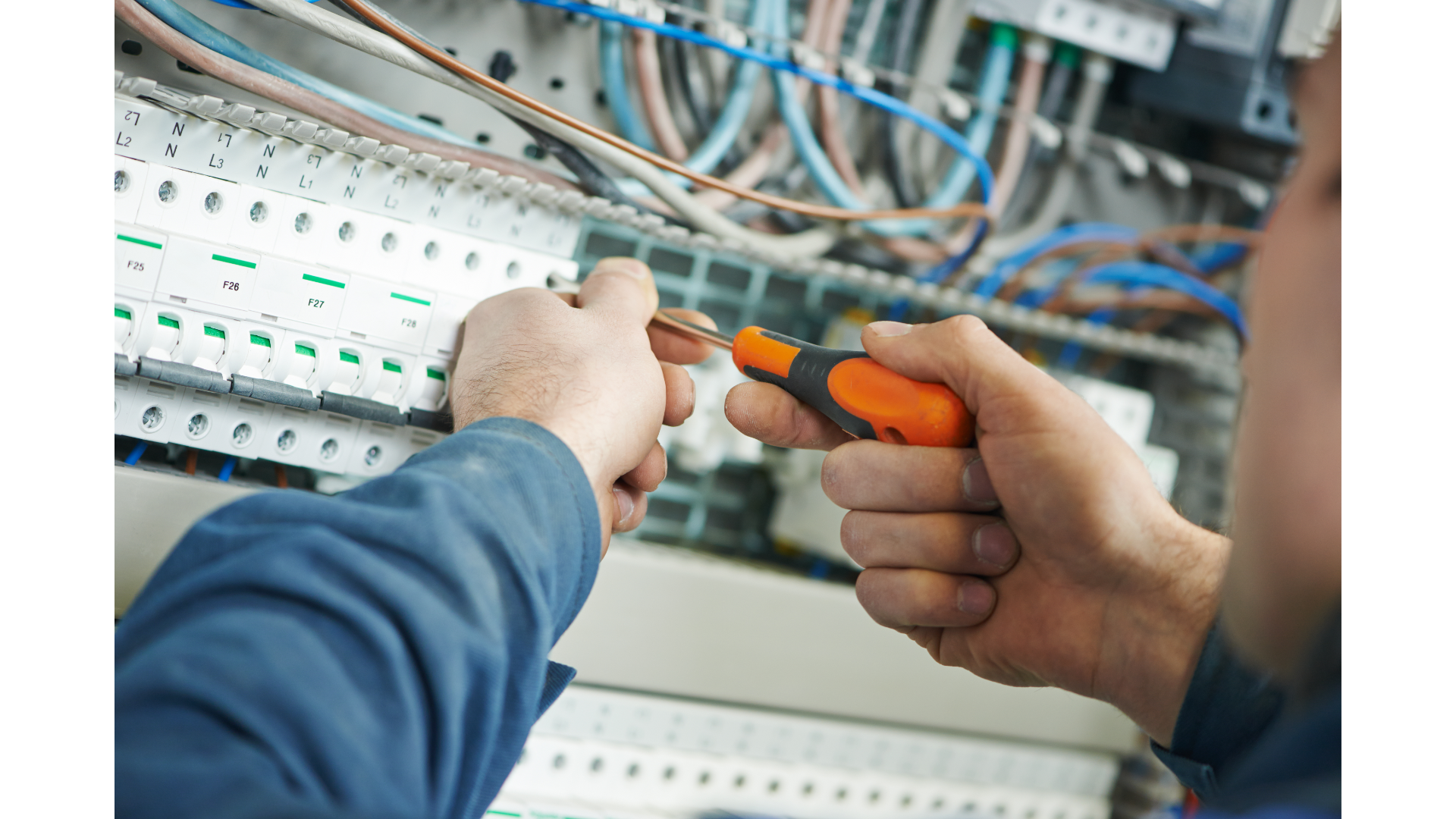 A man is working on an electrical box with a screwdriver.