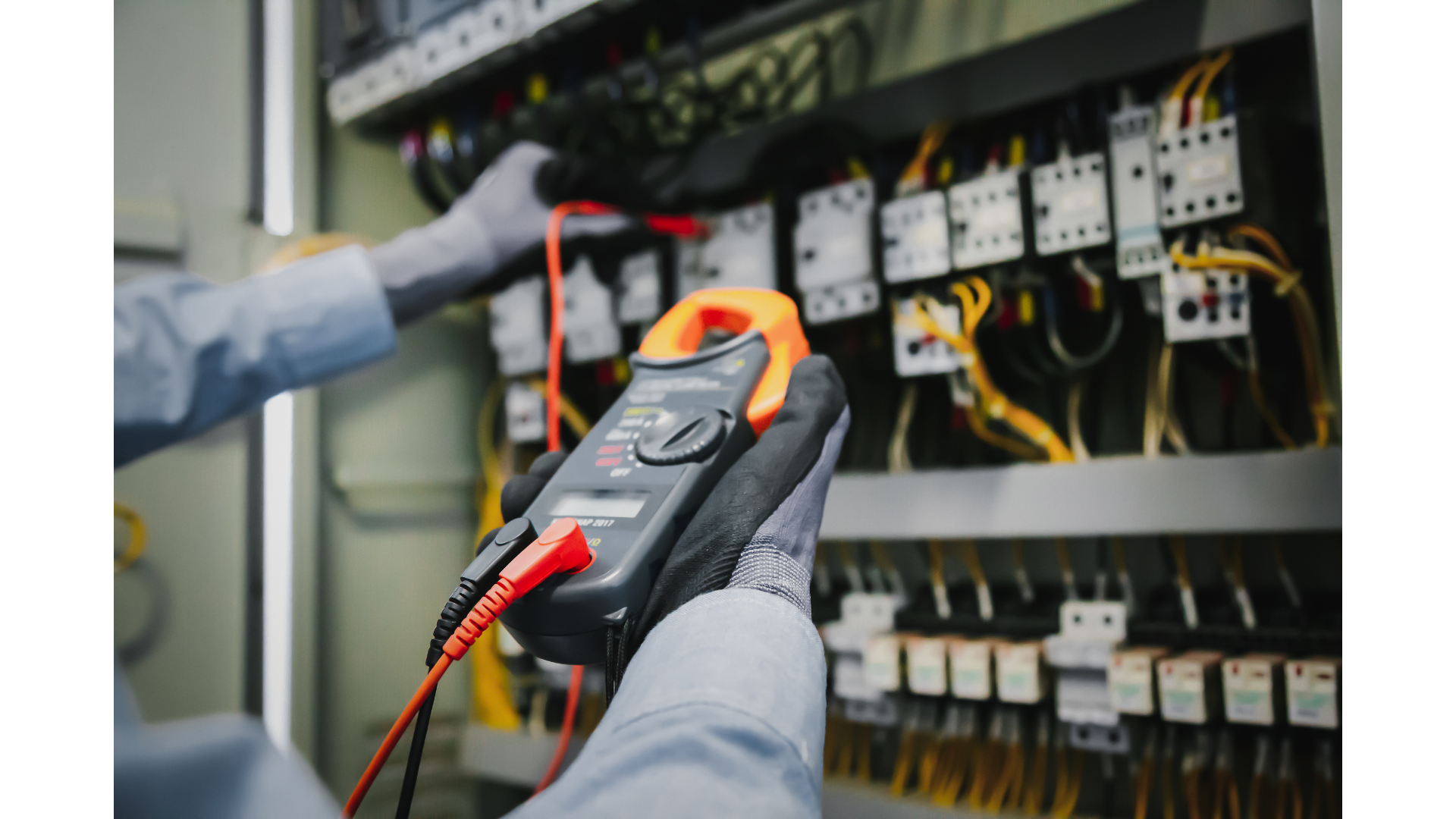 An electrician is using a clamp meter to test a circuit board.