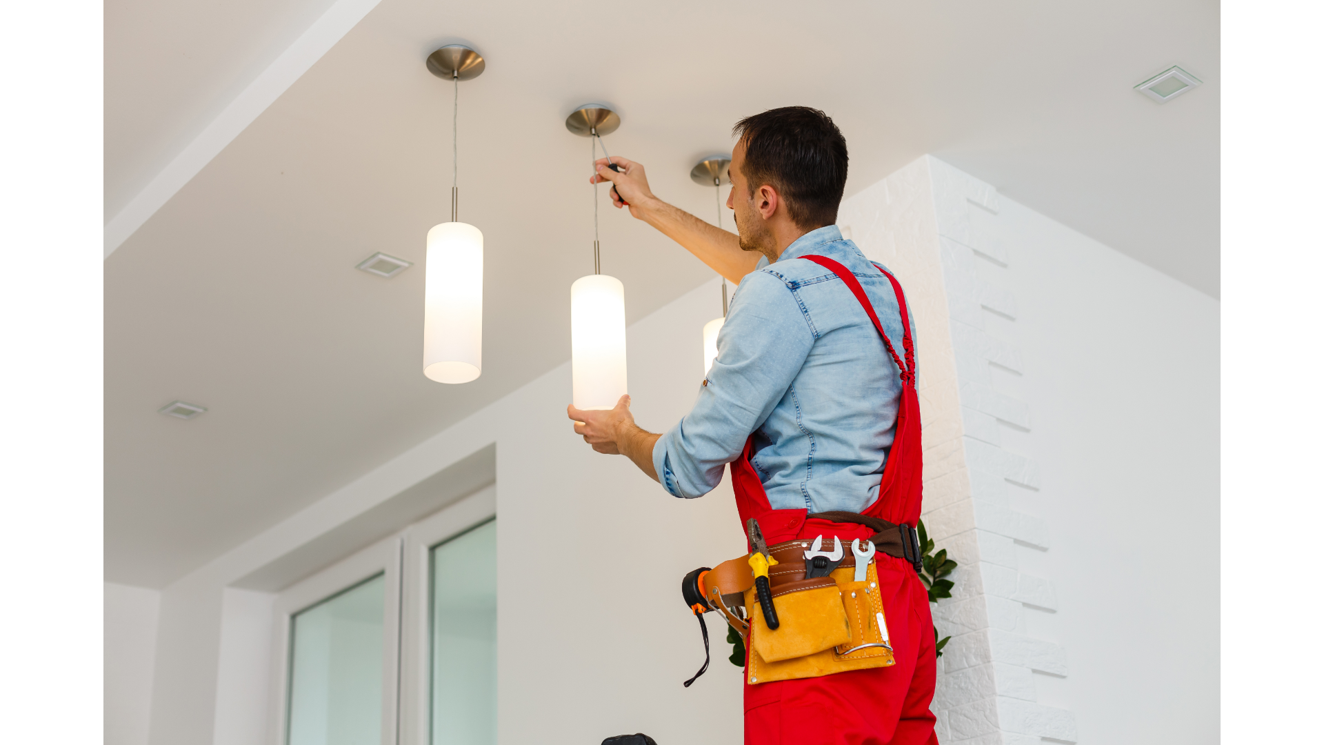 A man is installing a light fixture on the ceiling.