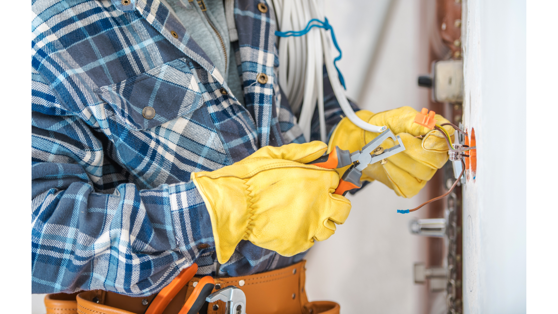 An electrician is working on a wall with a pair of pliers.
