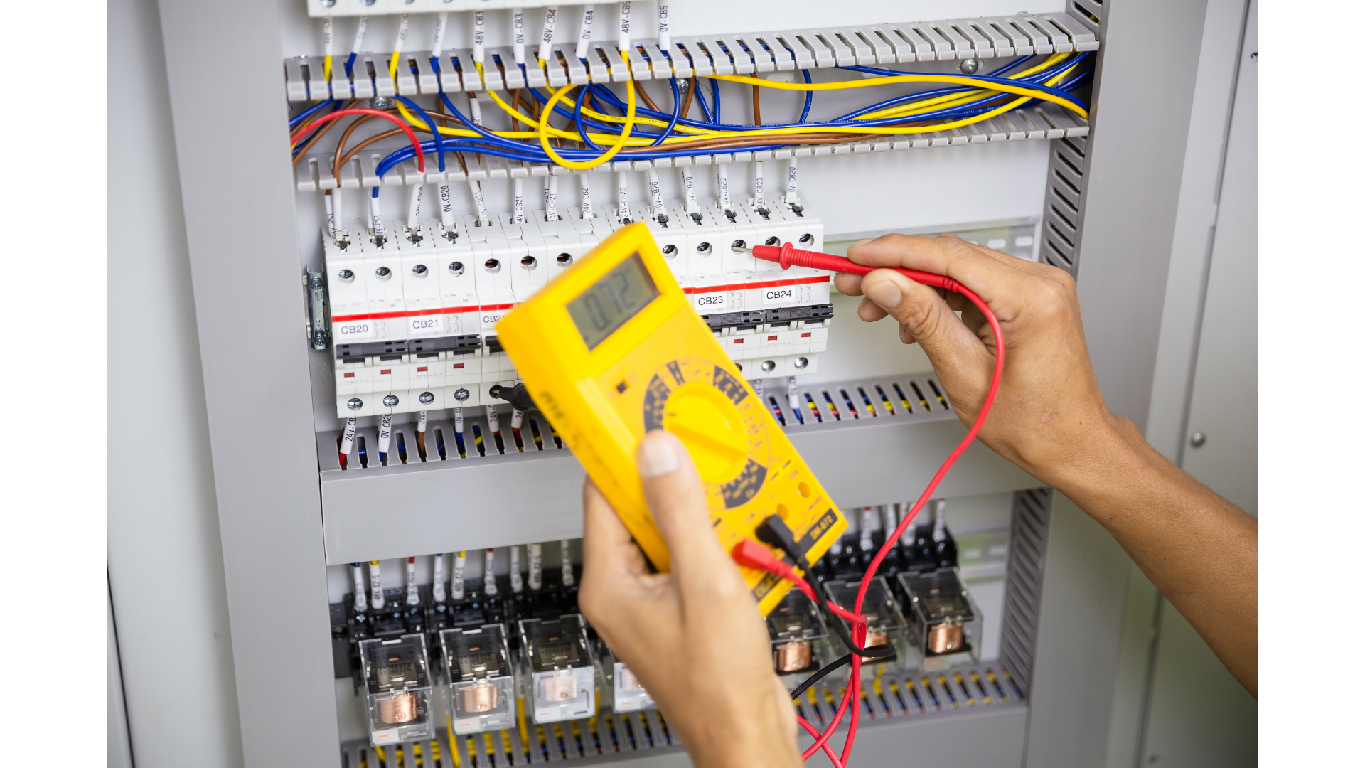 A person is using a digital multimeter to test a circuit board.