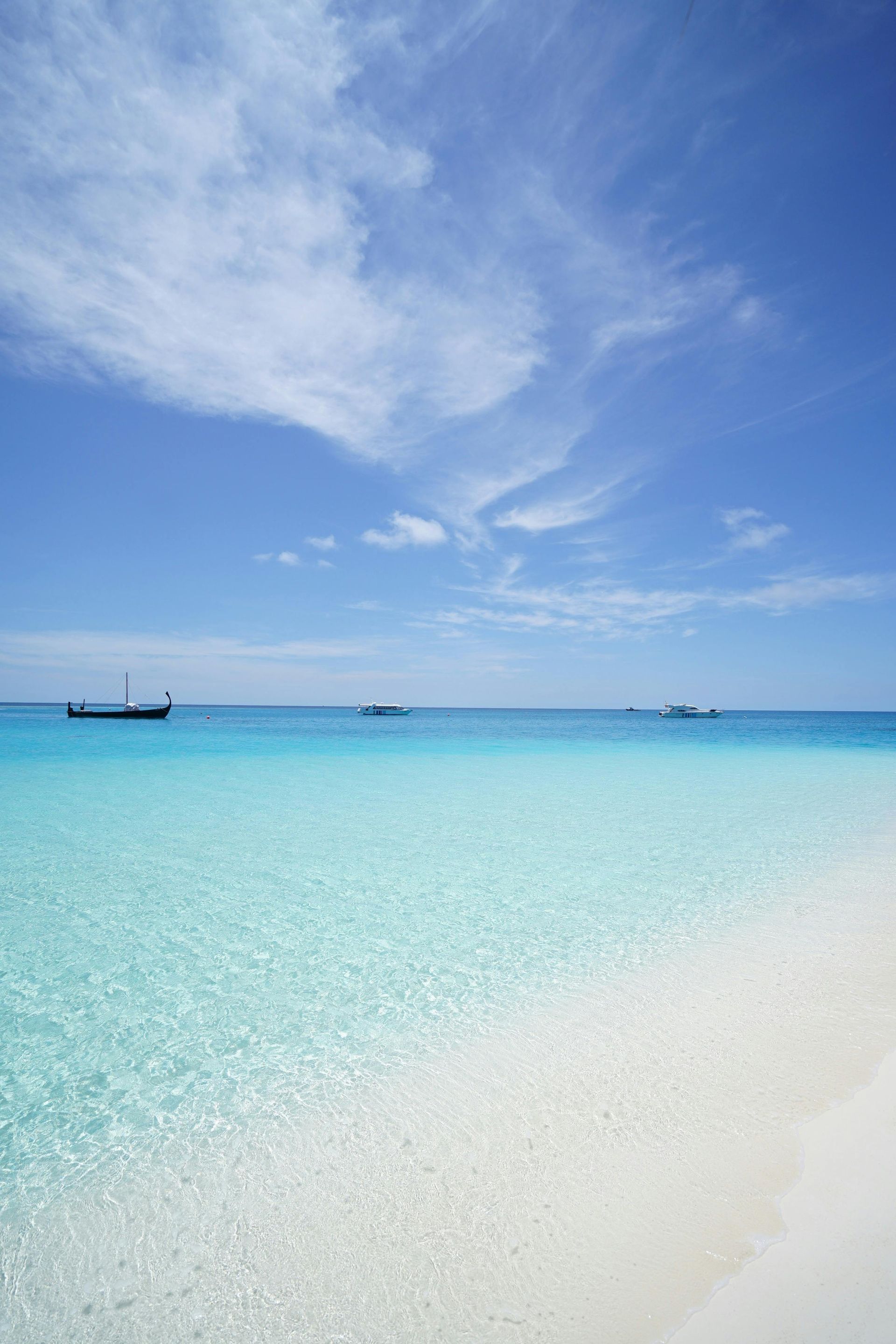 White sand beach, clear turquoise water, blue sky, longtail boat, sunny day.