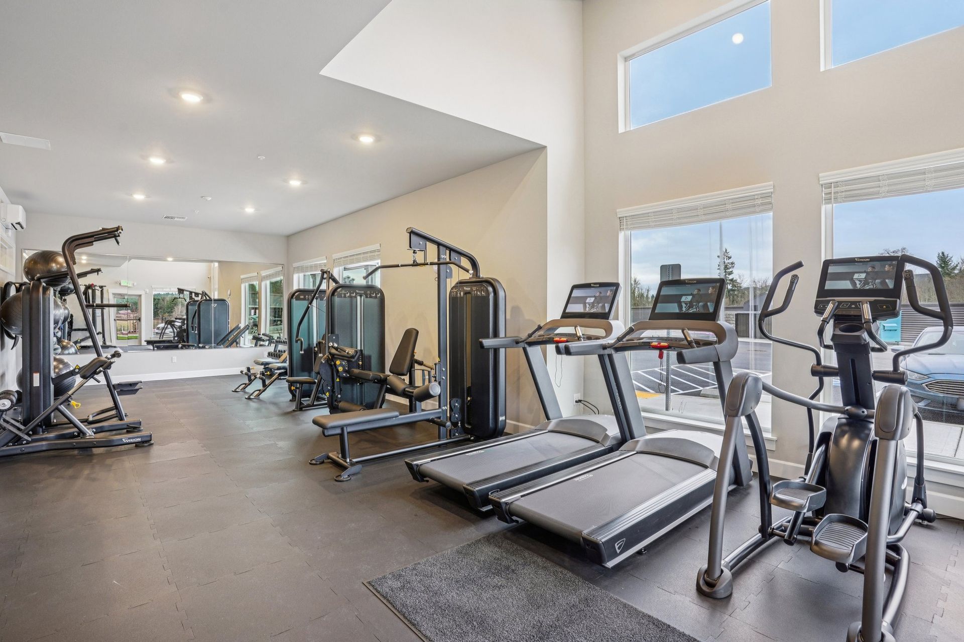 Modern gym with treadmills, ellipticals, and weight machines in a bright room