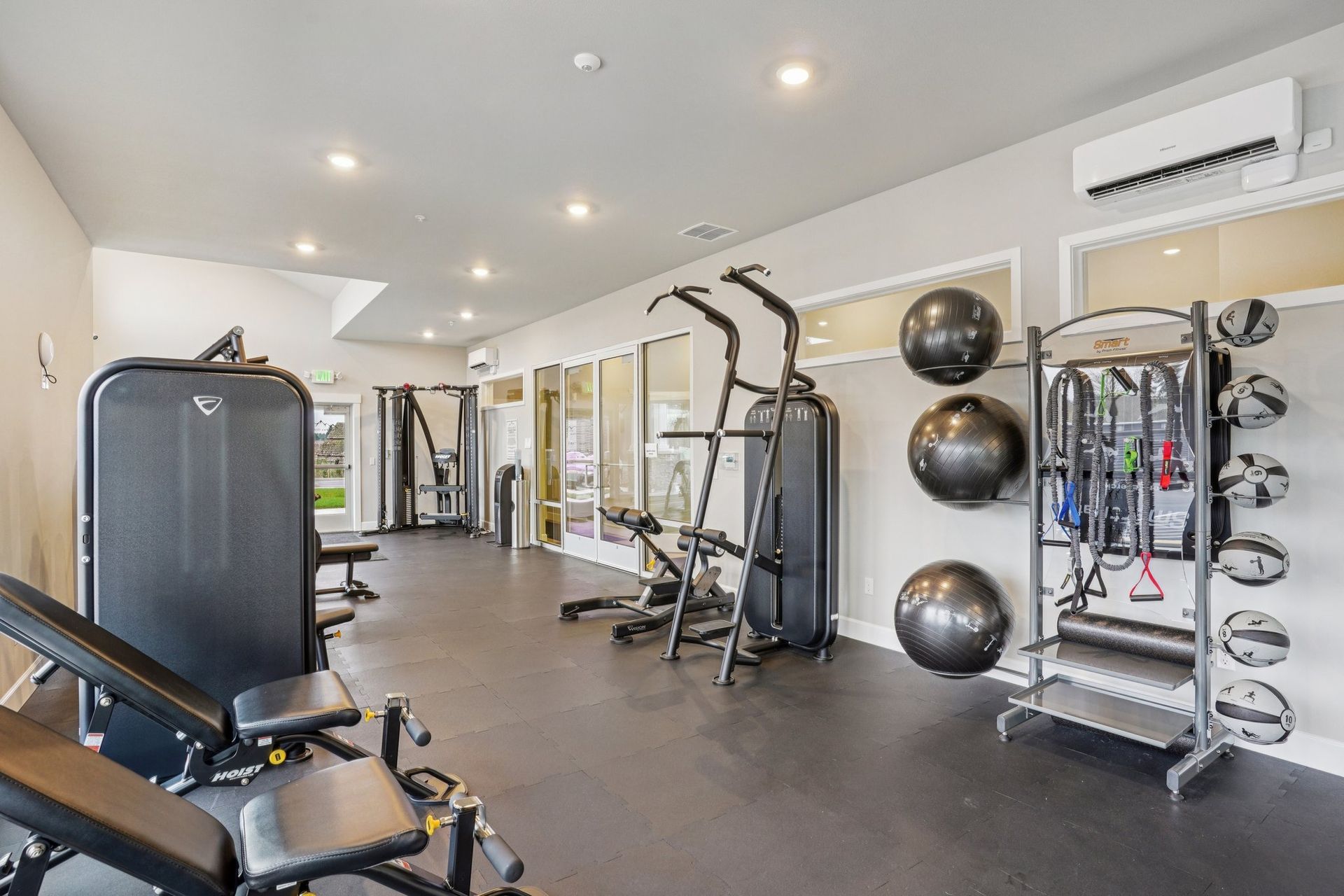 Modern gym interior with exercise machines, stability balls, mirrors, and wall-mounted air conditioners