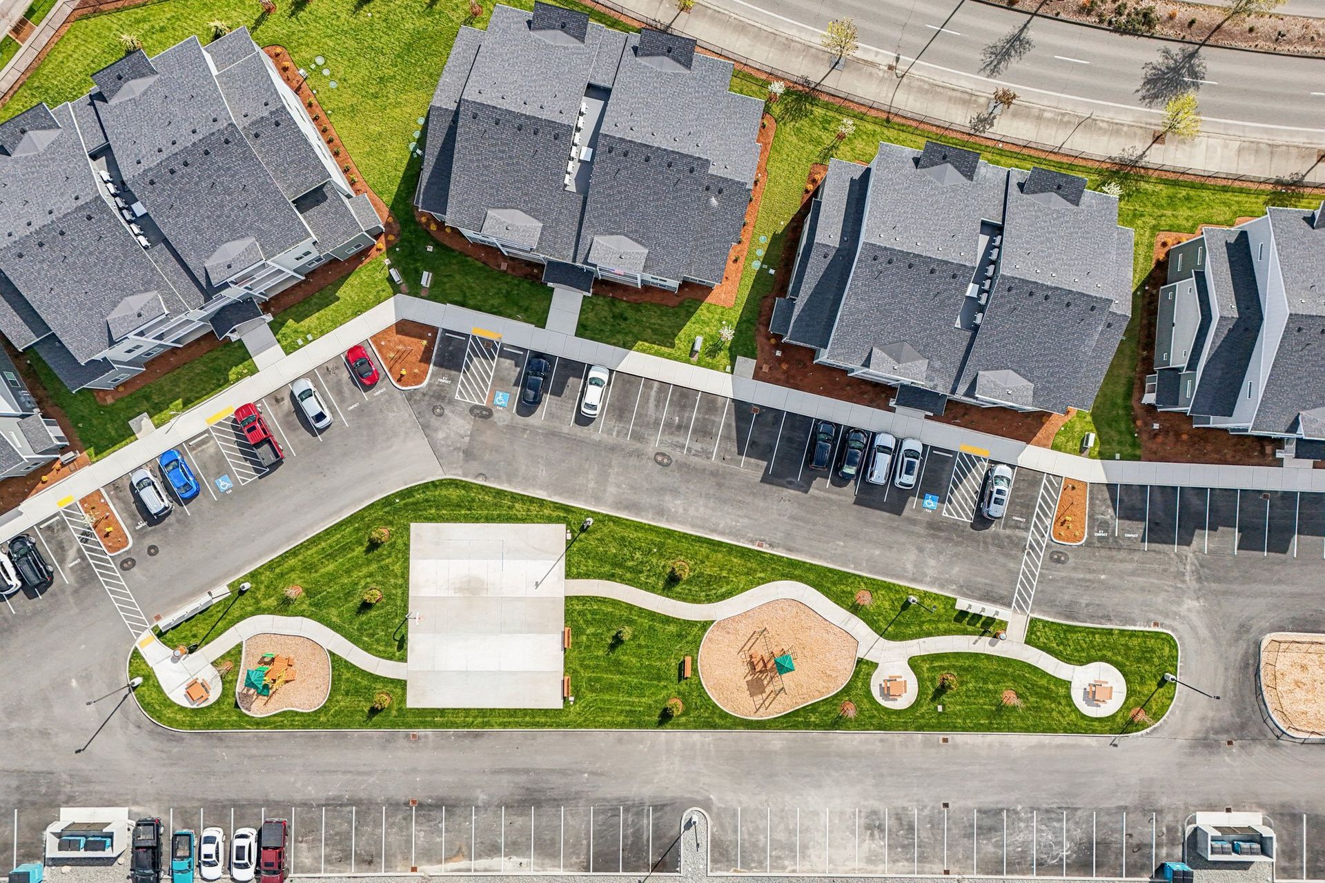 Aerial view of a residential courtyard with parking lots, sidewalks, and landscaped green spaces