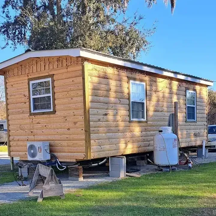 A small wooden house with a propane tank in front of it.