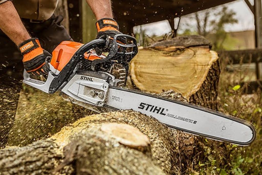 Chainsaw cutting through thick tree trunk during removal, worked on by Top'em & Drop'em in Midway, FL.