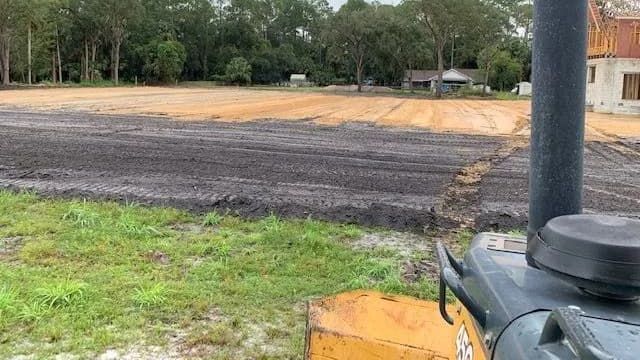 Graded construction site in Sanford, FL, showing a freshly leveled lot with visible soil layers and 