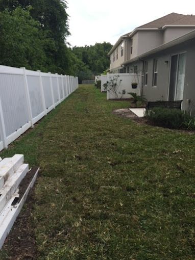 There is a white fence in the backyard of a house.