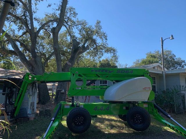 A green crane is parked in front of a house.