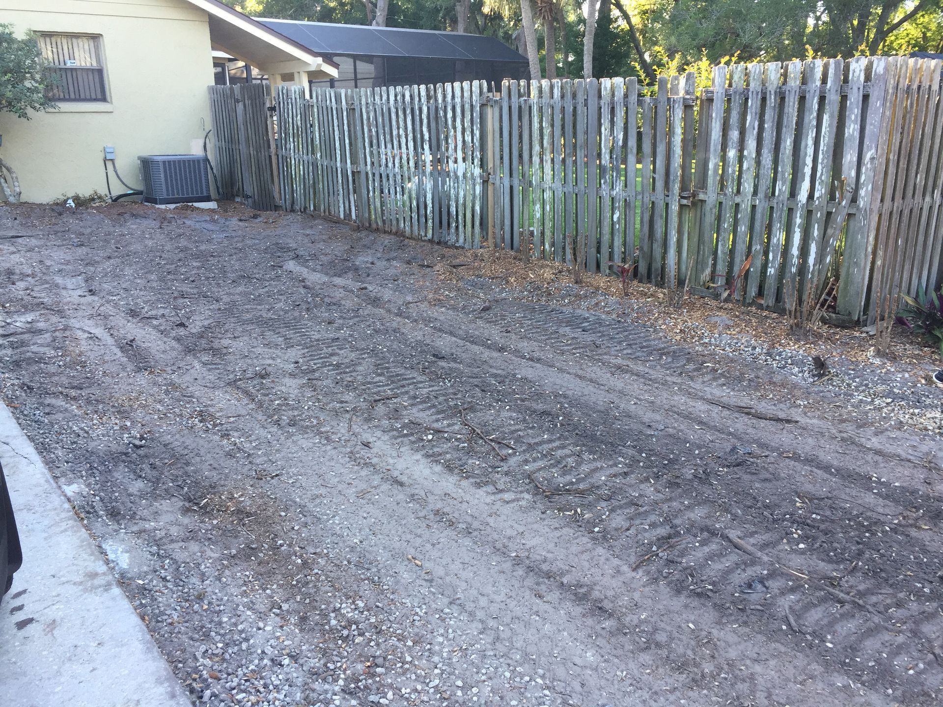 A dirt road with a wooden fence in the background