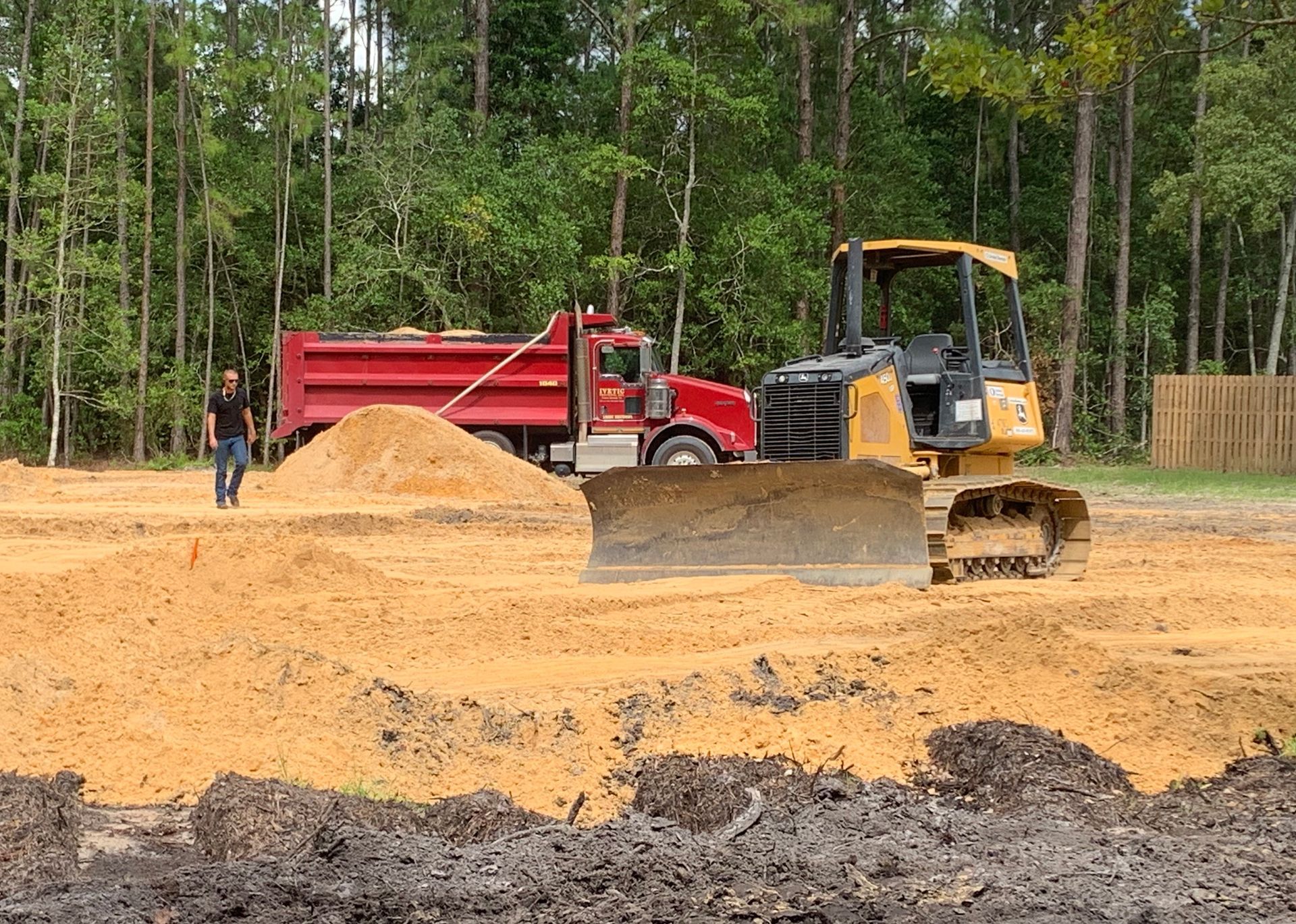 A bulldozer is moving dirt on a construction site next to a dump truck.