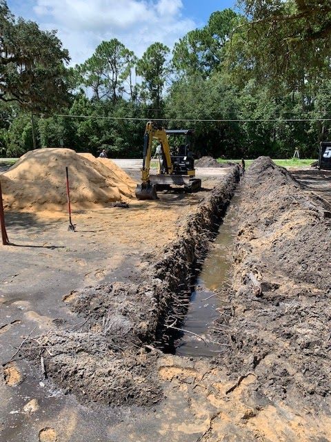 A yellow excavator is digging a trench in the dirt.