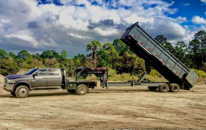 Top’em and Drop’em truck with a raised hydraulic dump trailer unloading fill dirt at a cleared job s