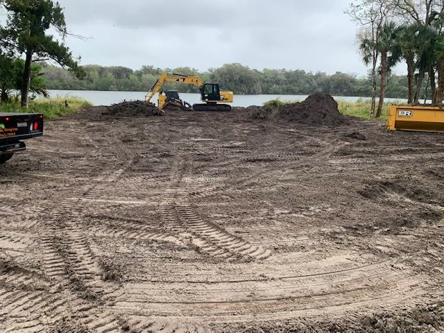 A large excavator is sitting in the middle of a dirt field.