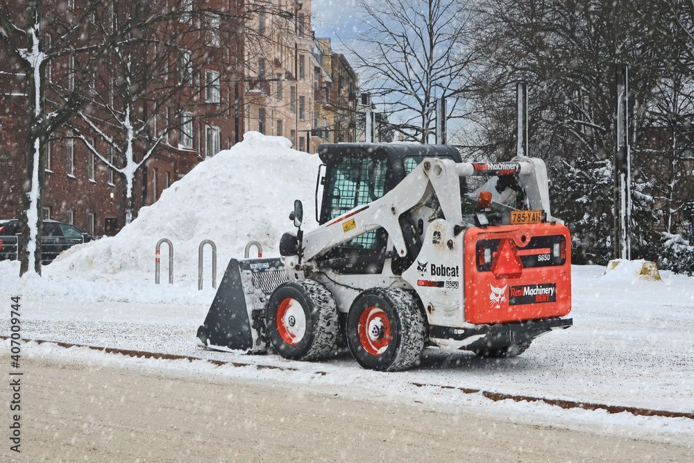 A bulldozer is clearing snow from the side of the road.
