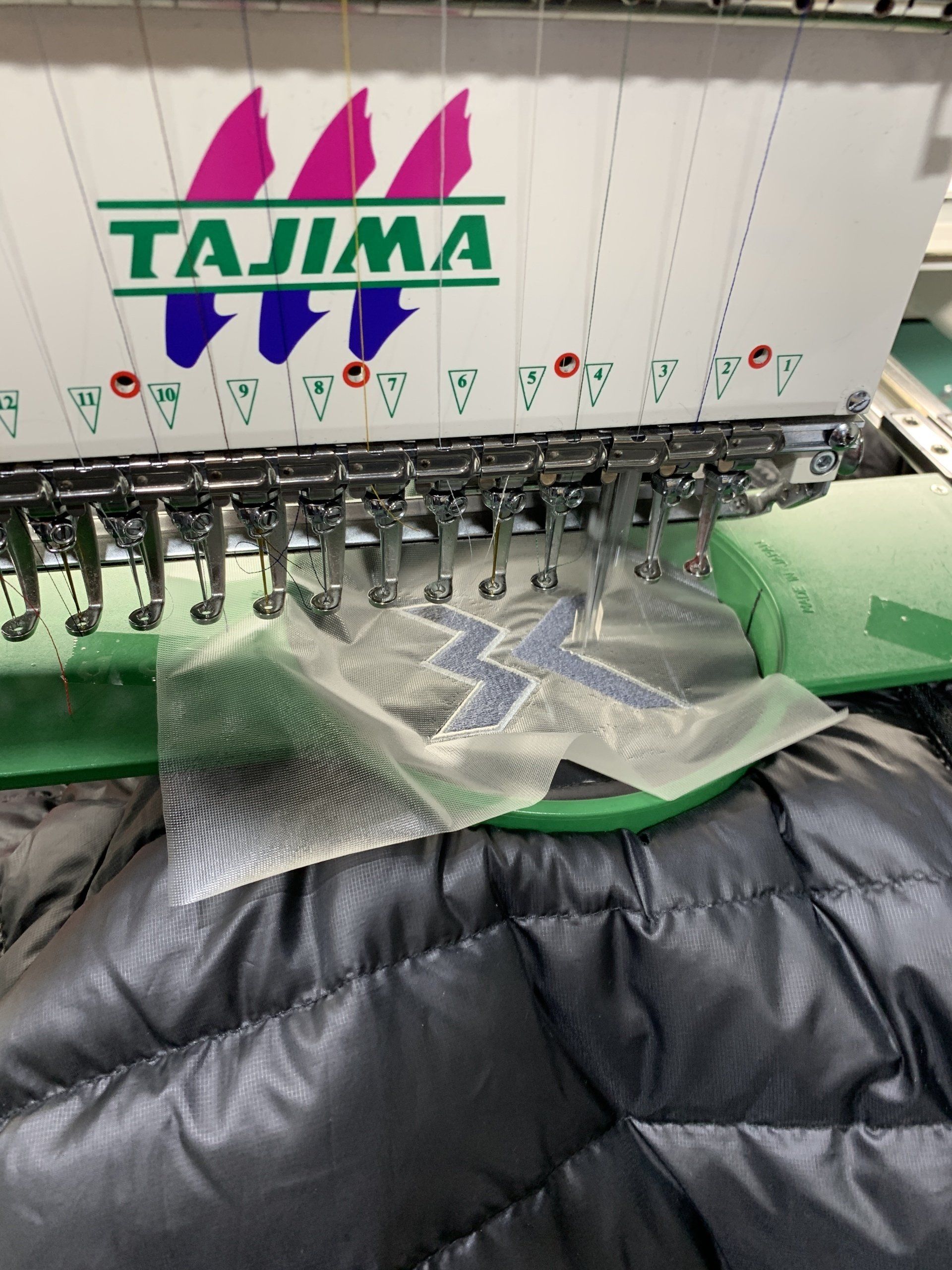 A tajima sewing machine is working on a jacket