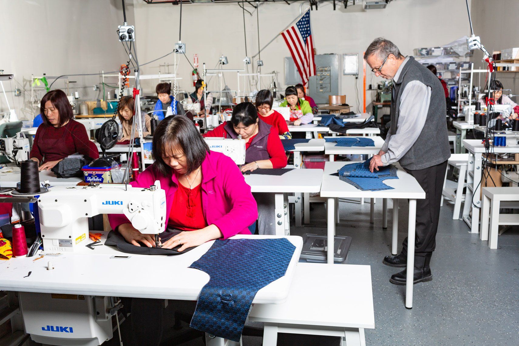 A group of people are working on sewing machines in a factory.