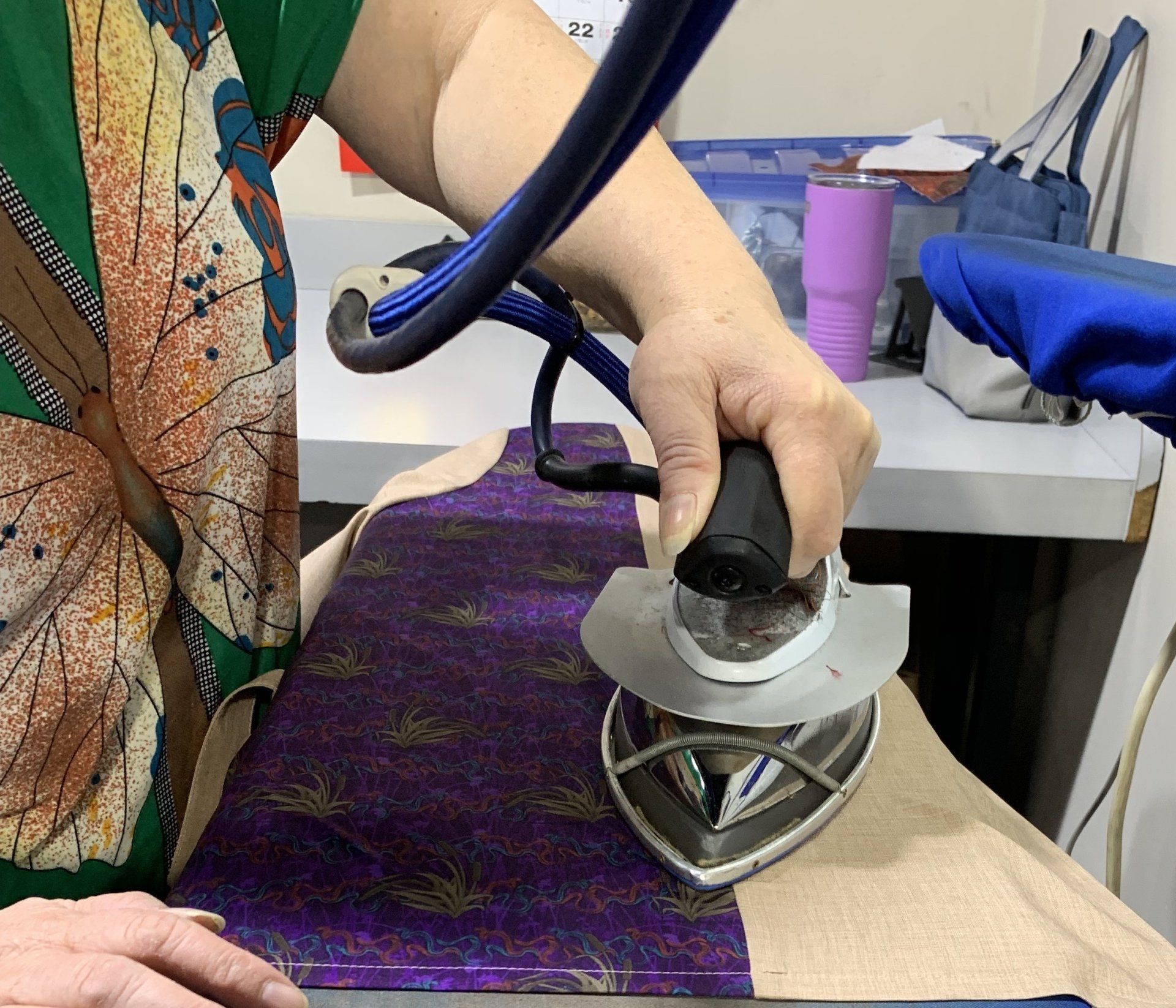 A person is ironing a piece of purple fabric