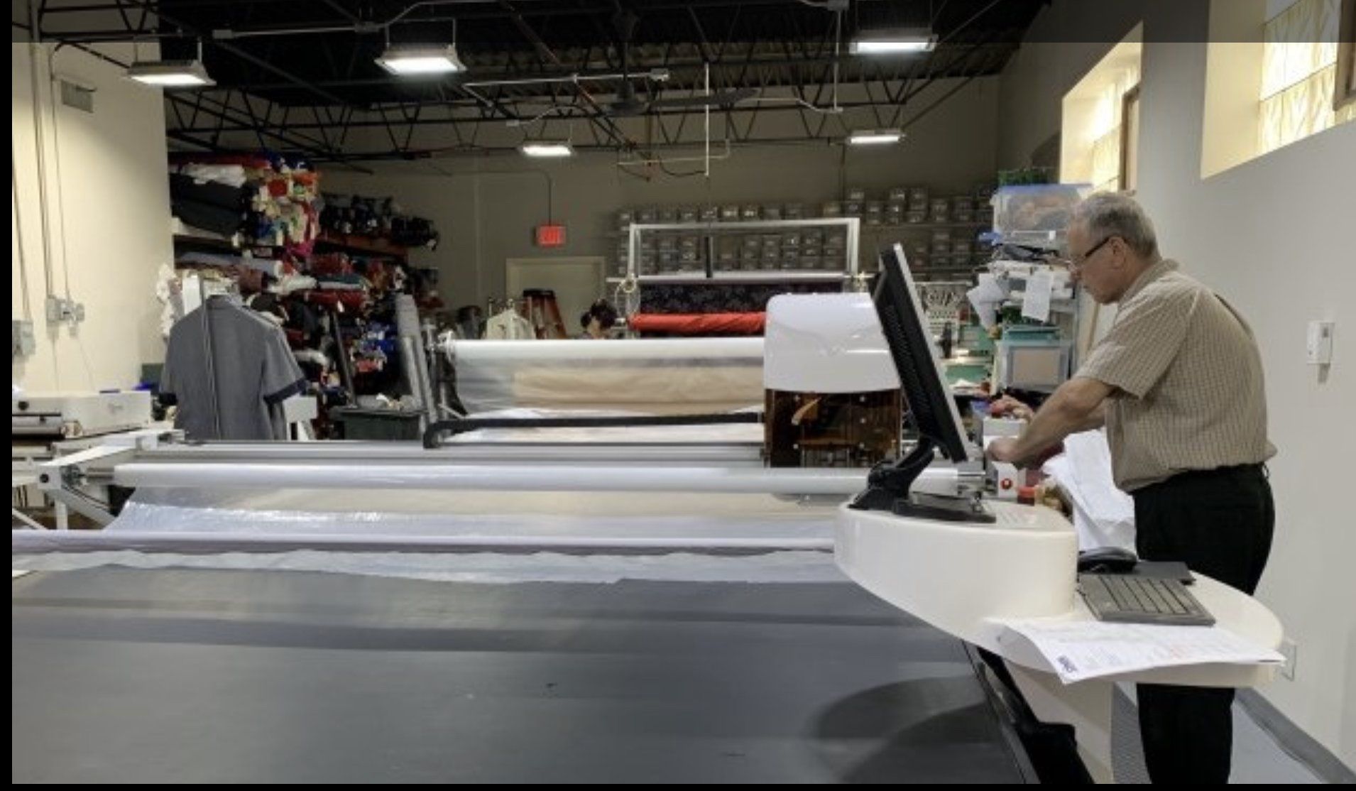 A man is standing in front of a computer in a factory.