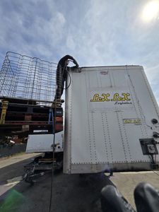 A man on a ladder is working on the back of a box truck