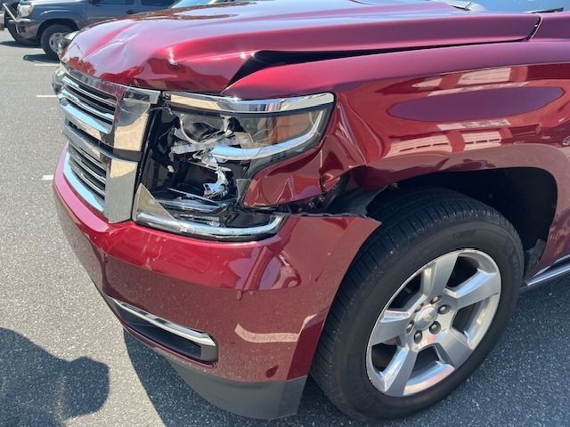 Red SUV with front-end damage; crumpled hood and broken headlight.