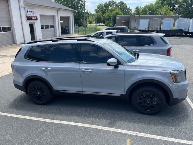 Gray Kia Telluride SUV with black wheels parked outside a building.