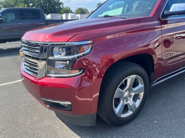 Red Chevrolet Suburban SUV, front view, parked outdoors.
