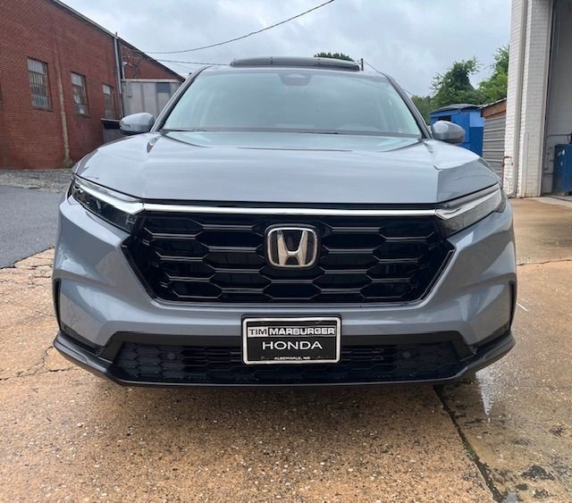 Gray Honda CR-V SUV, black grill and bumper, parked outside near a brick building.