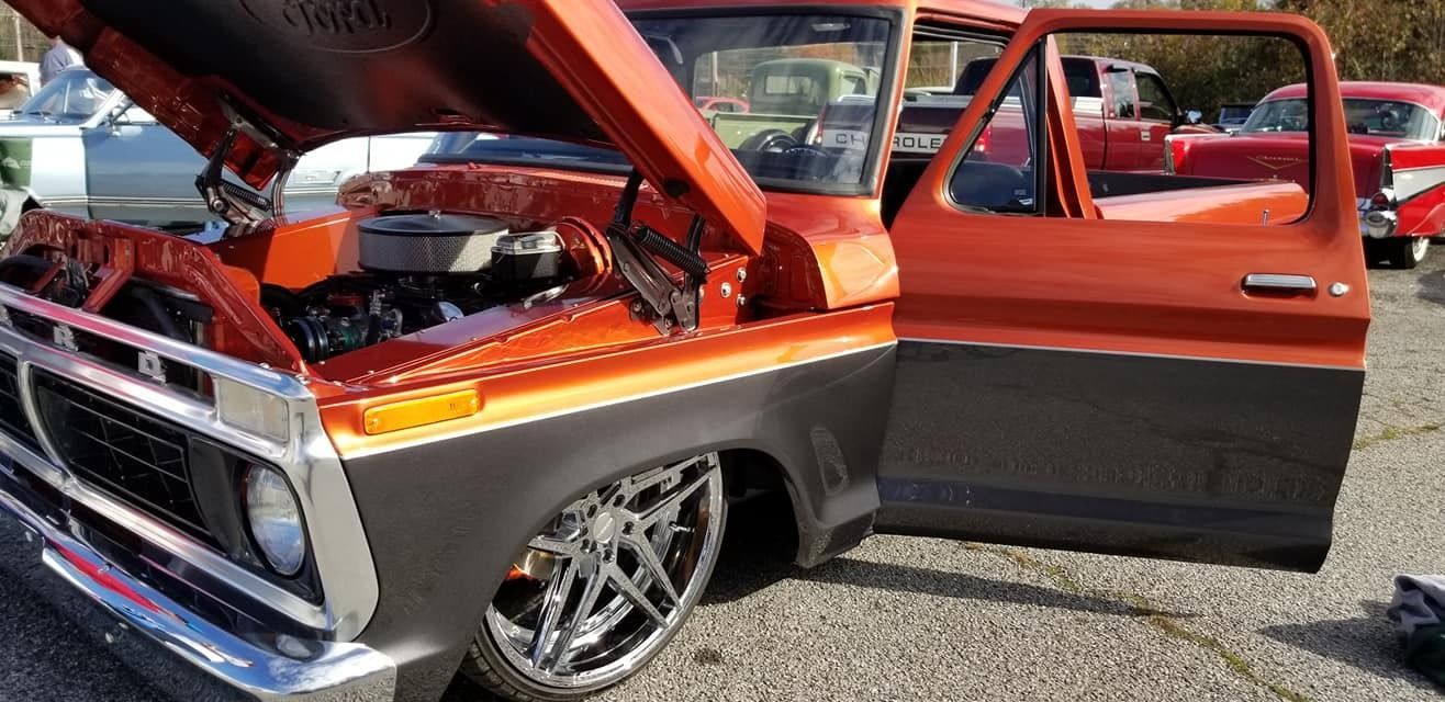 Orange and black custom vintage truck with open hood and door.