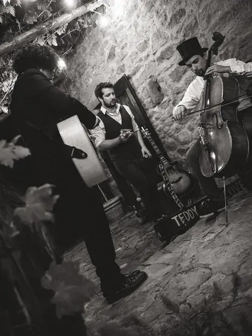 Straßenmusiker spielen in einer Steingasse mit Gitarre, Klarinette und Cello.